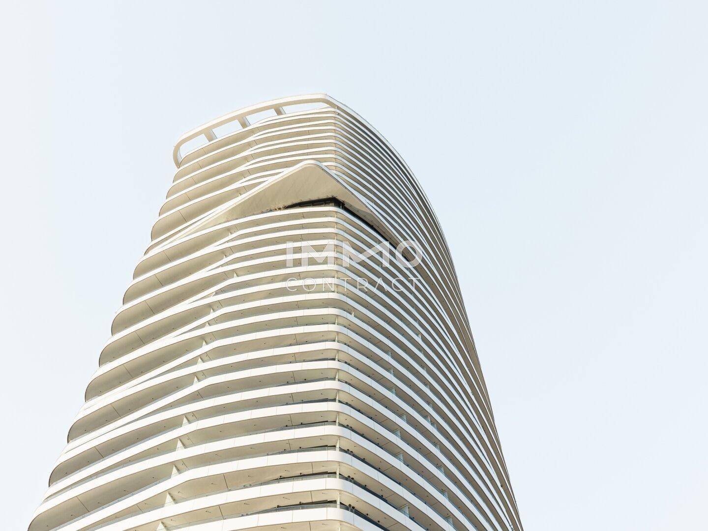 Moderne Hochhausfassade mit einzigartigem, geschwungenem Design unter klarem Himmel.