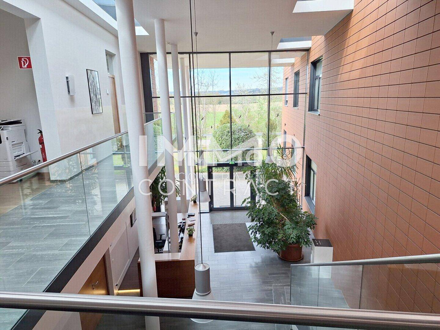 Helle und moderne Lobby mit hohen Decken, Glasgeländern und einem Empfangsbereich, der viel natürliches Licht erhält.