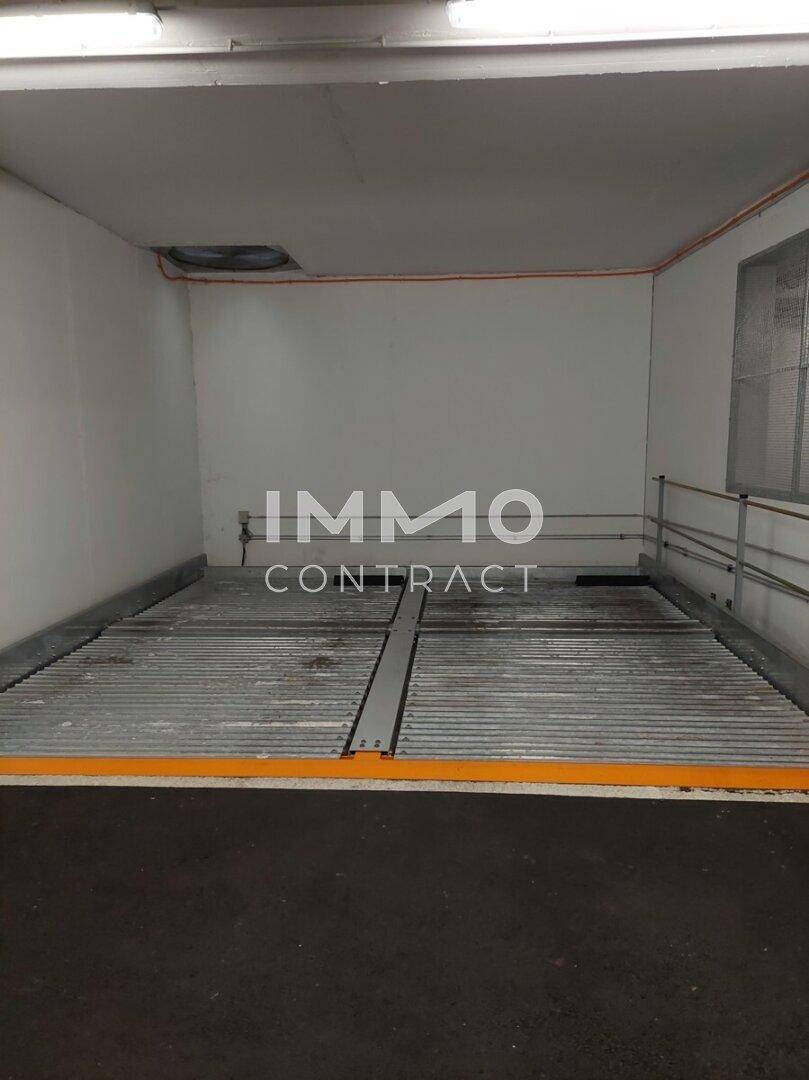 Mechanisches Parksystem in einer Tiefgarage mit orangefarbener Markierung und Lüftung.
