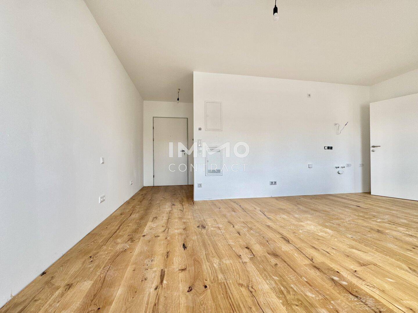 Leerer Raum mit Holzboden und weißen Wänden, vorbereitet für die weitere Gestaltung und Nutzung.
