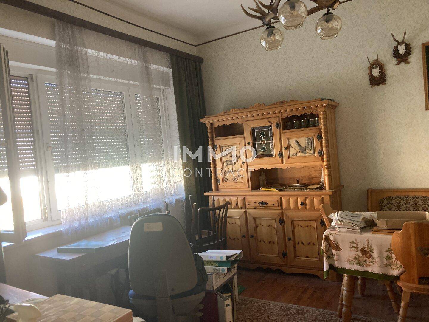 Traditionell eingerichteter Wohn-Essbereich mit rustikalen Holzmöbeln und Jagdtrophäen.