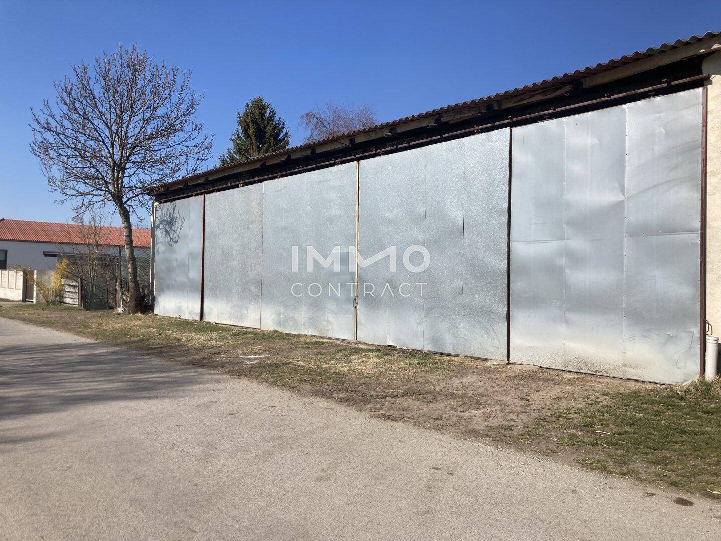 Lange, mit Metall verkleidete Scheune oder Lagerhalle an einer ländlichen Straße.