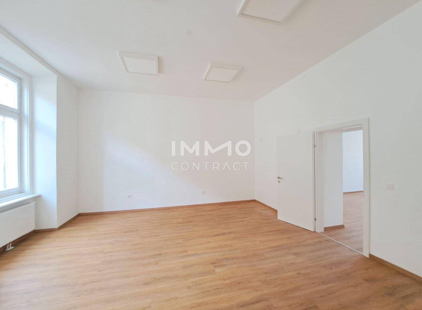Geräumiger, heller Raum mit Holzboden und Zugang zu einem weiteren Zimmer, frisch renoviert.