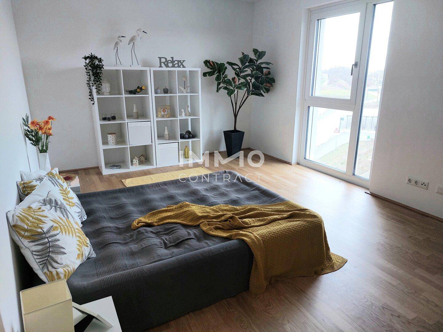 Geräumiges Schlafzimmer mit großem Fenster, Holzboden und moderner Einrichtung.