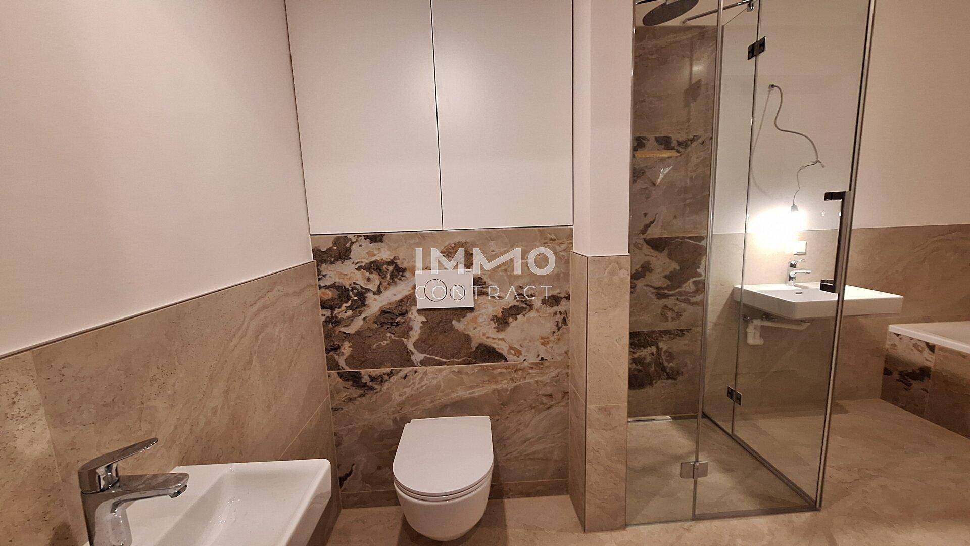 Modernes Badezimmer mit Dusche, Toilette und Waschbecken, ausgestattet mit beigefarbenen Fliesen.