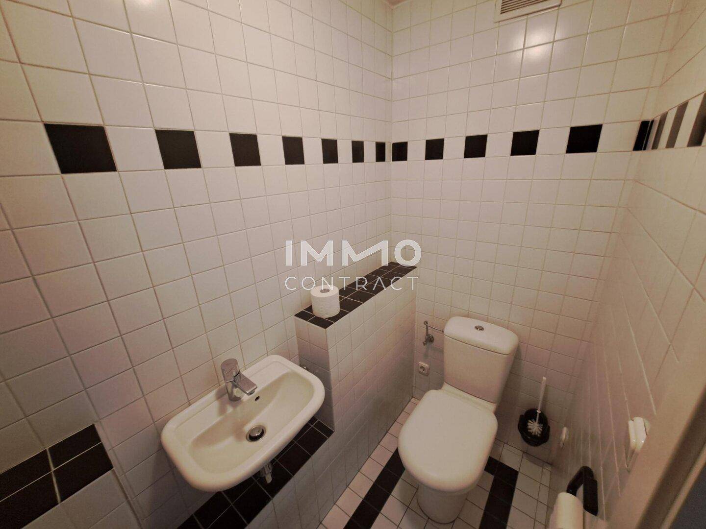 Kompakte Toilette mit Waschbecken und WC, ausgestattet mit weißen Fliesen und schwarzen Akzenten.