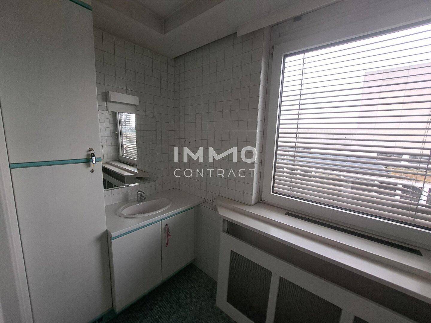 Helles Badezimmer mit Waschbecken, Spiegelschrank und Fenster, das für natürliche Belüftung sorgt.