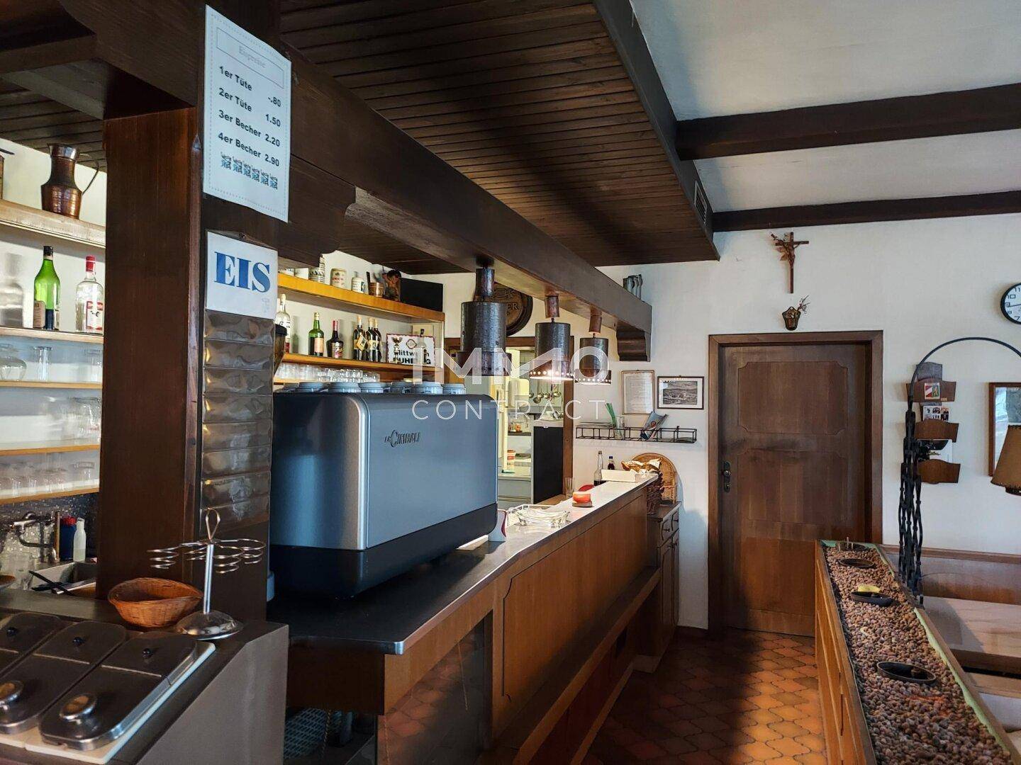 Traditionelle Bar mit Holzelementen, Kaffeemaschine und Regalen für Getränke in einem Gasthof.