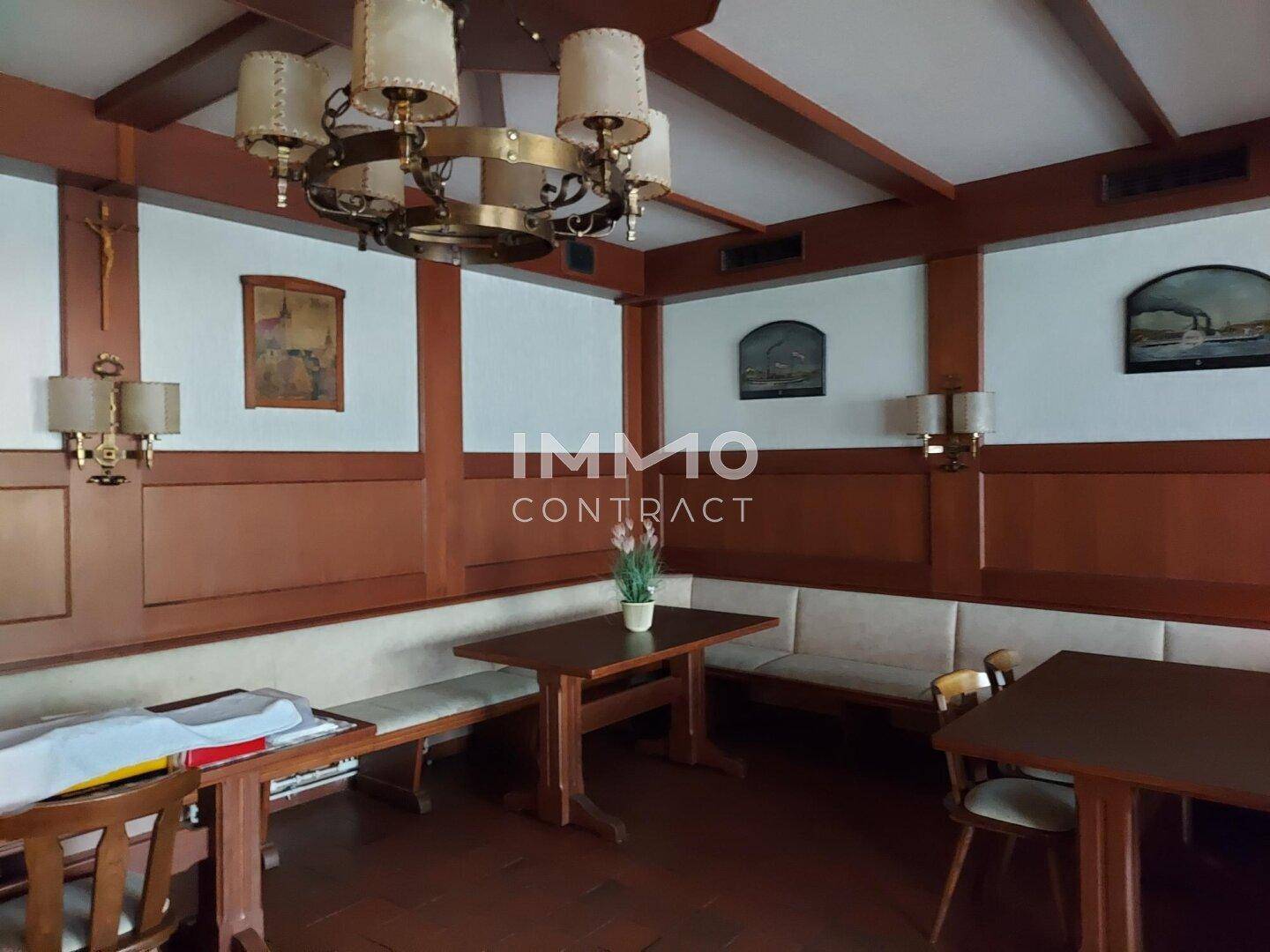 Rustikaler Essbereich mit Holztäfelung, Bänken und traditionellen Deckenleuchten in warmen Tönen.