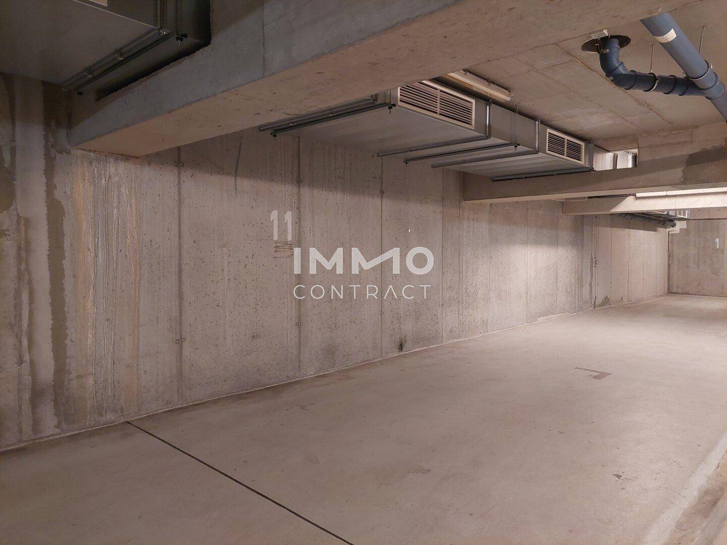 Leerer Stellplatz in der Tiefgarage mit Betonwänden und Deckeninstallationen.
