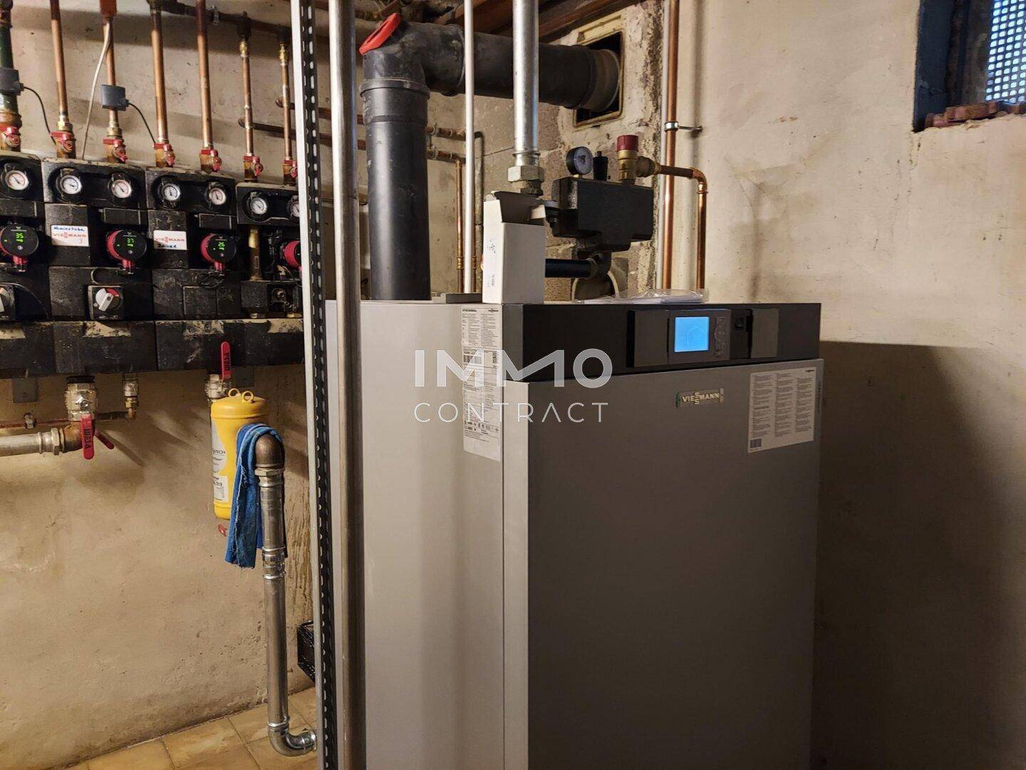 Heizungsraum mit moderner Heizungsanlage und Kupferrohren an der Wand für die Warmwasserversorgung.