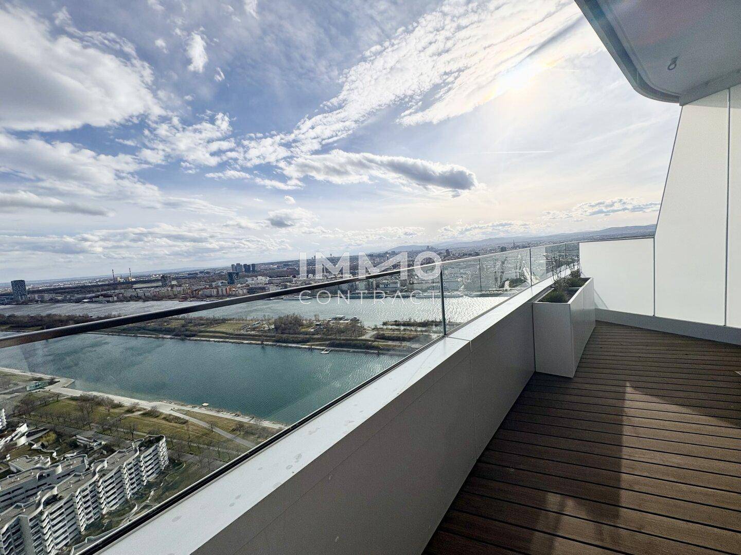 Weitläufige Terrasse mit Holzboden und Glasbrüstung, bietet einen Panoramablick auf den Fluss und die Stadt.