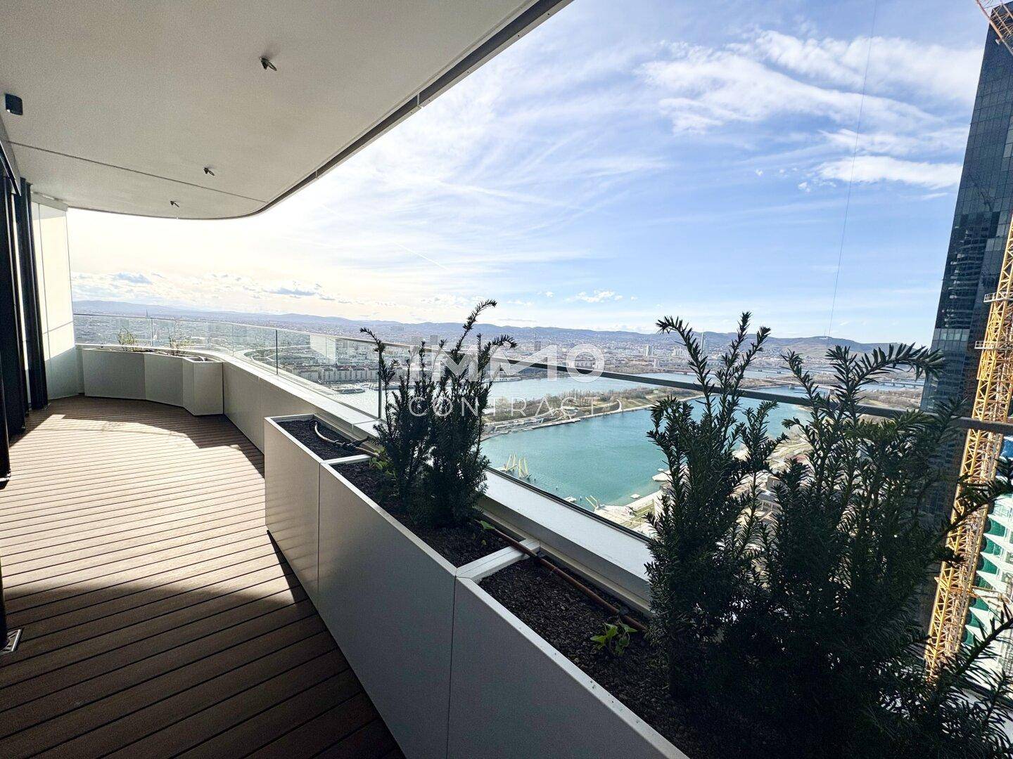 Moderne Terrasse mit Holzboden und Pflanzenkübeln, bietet einen weiten Blick auf die Stadt und den Fluss.