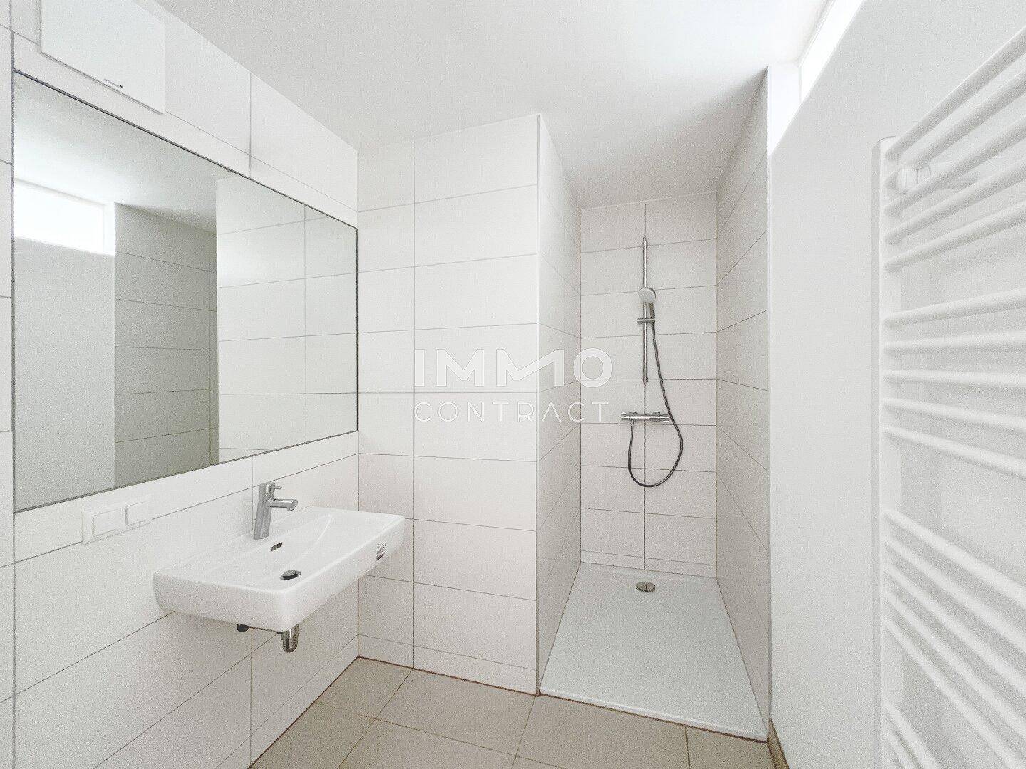 Modernes Badezimmer mit weißen Fliesen, Einzelwaschbecken und ebenerdiger Dusche.