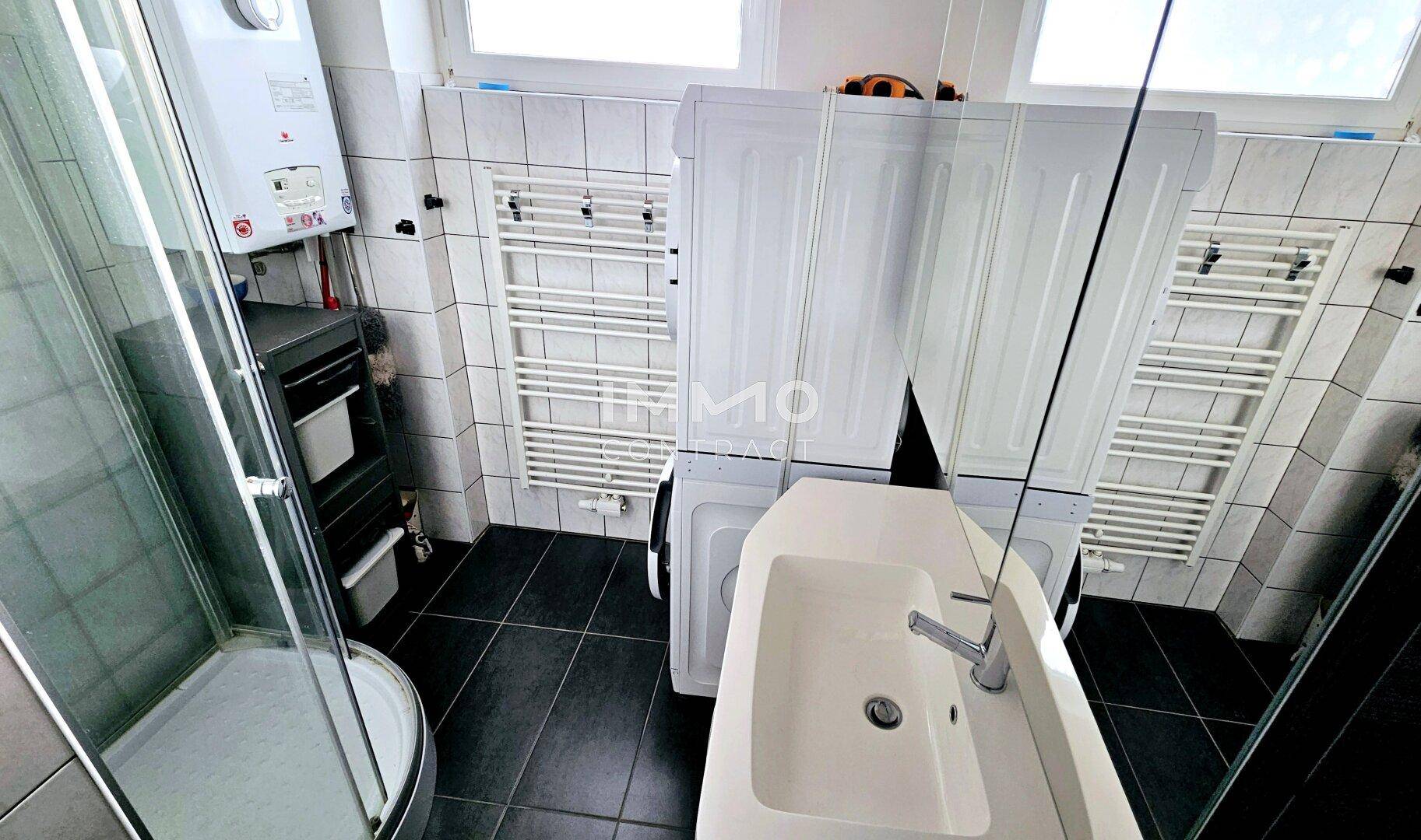 Funktionales Badezimmer mit Duschkabine, Waschbecken, Waschmaschine und beheizten Handtuchhaltern.