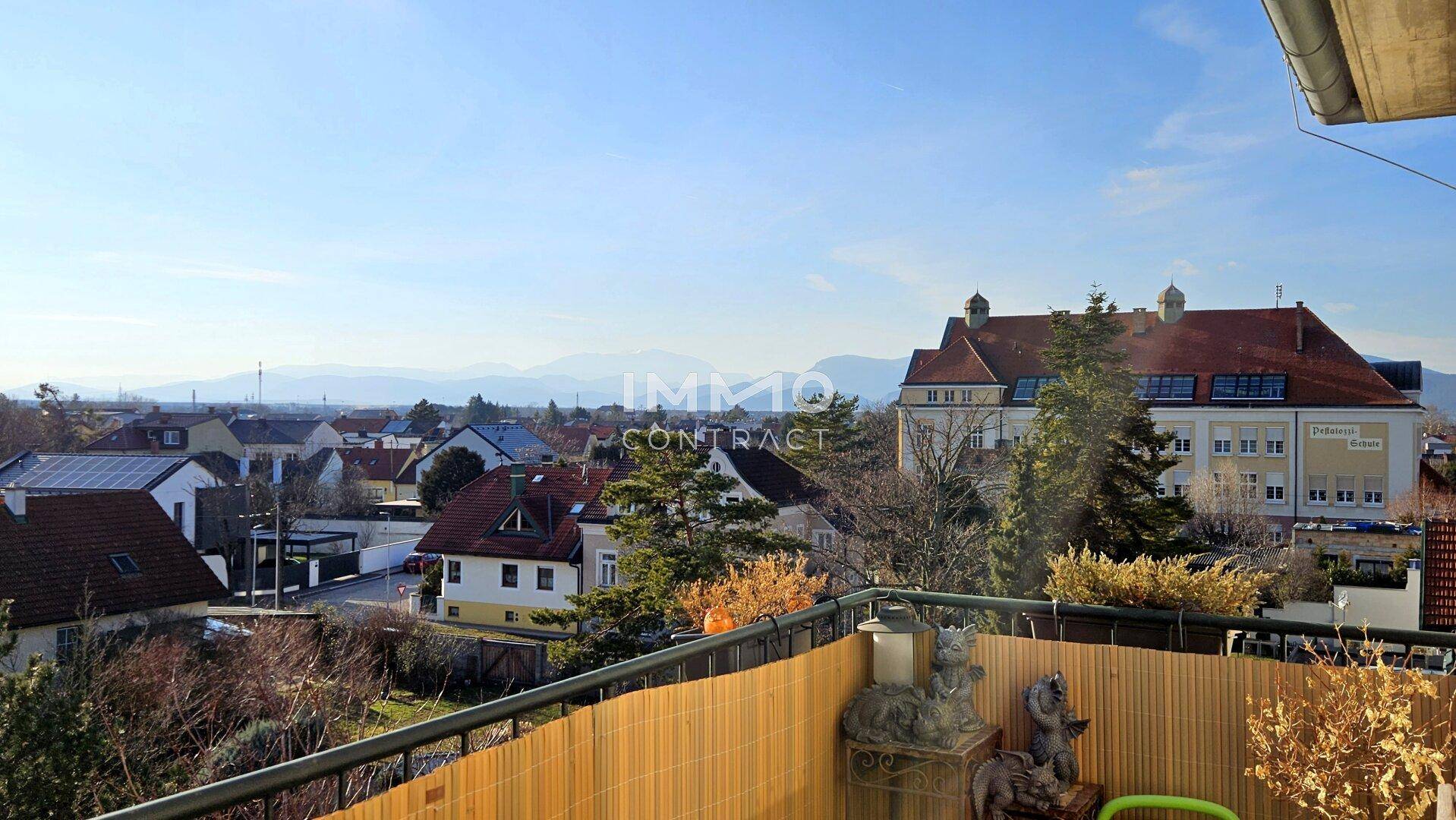 Sonniger Balkon mit weitem Blick über die Stadt und die dahinterliegenden Berge.