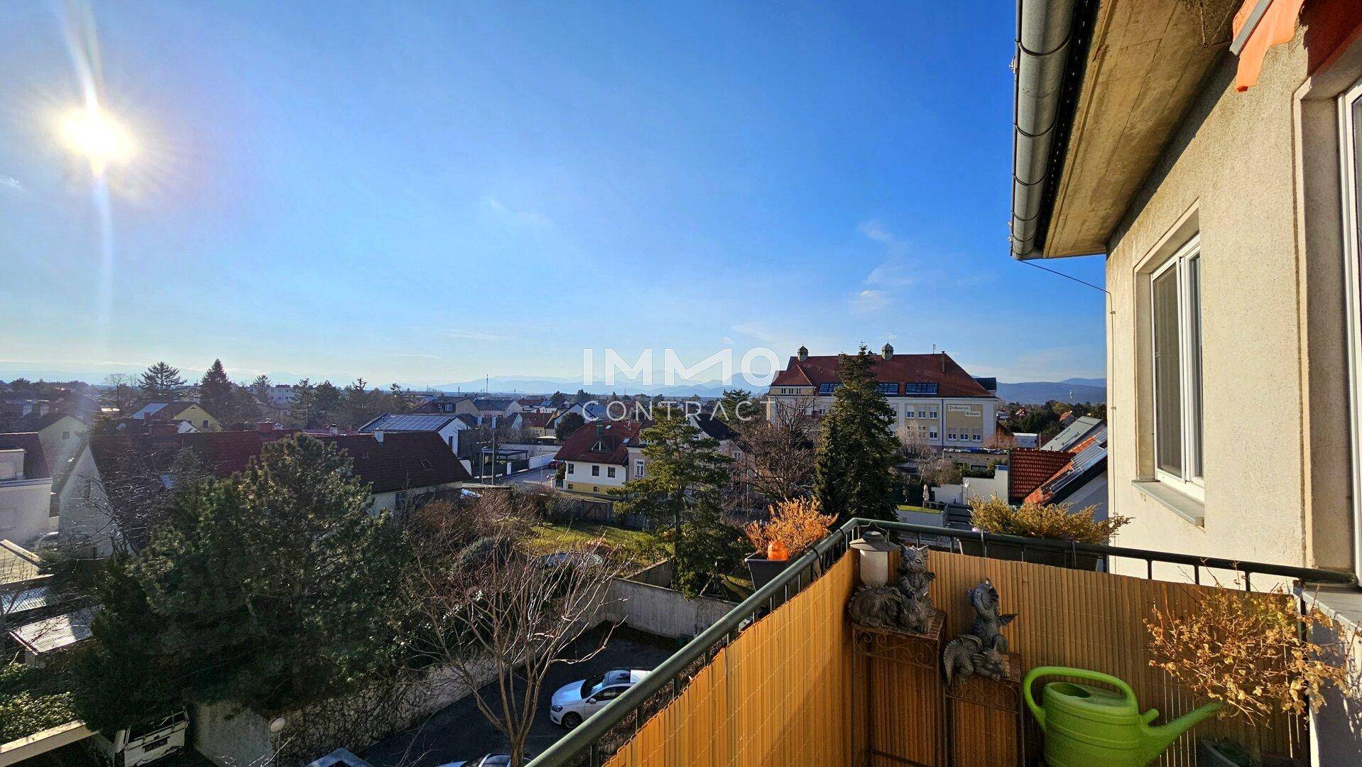 Sonniger Balkon mit Blick auf die umliegende Nachbarschaft und den blauen Himmel.