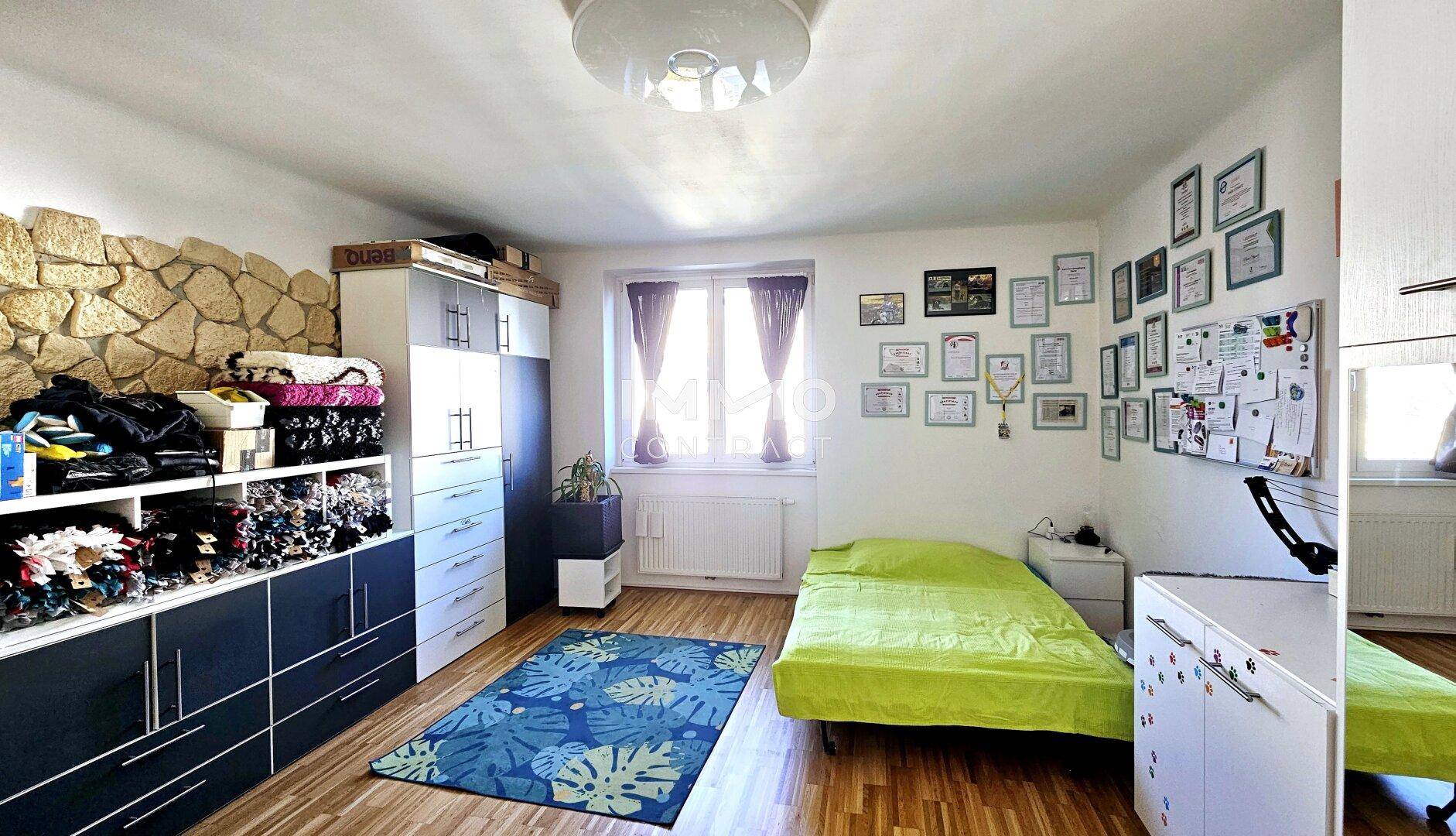 Helles Schlafzimmer mit Holzboden, Einzelbett und großem Schrank mit viel Stauraum.