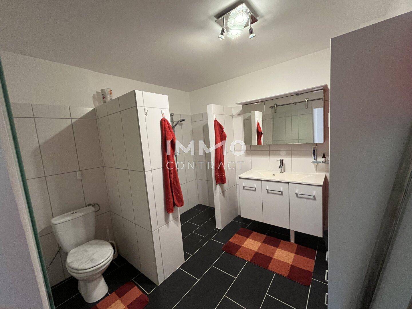 Modernes Badezimmer mit Dusche, WC und dunklen Bodenfliesen.