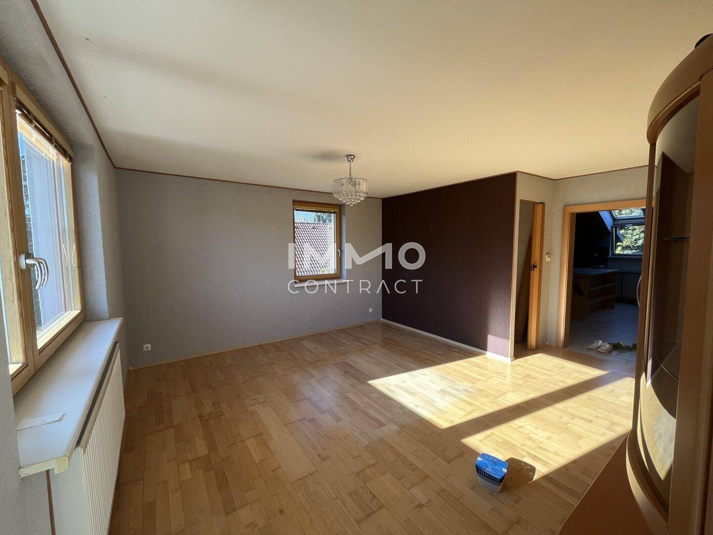 Helles Wohnzimmer mit Parkettboden, großen Fenstern und viel Tageslicht.
