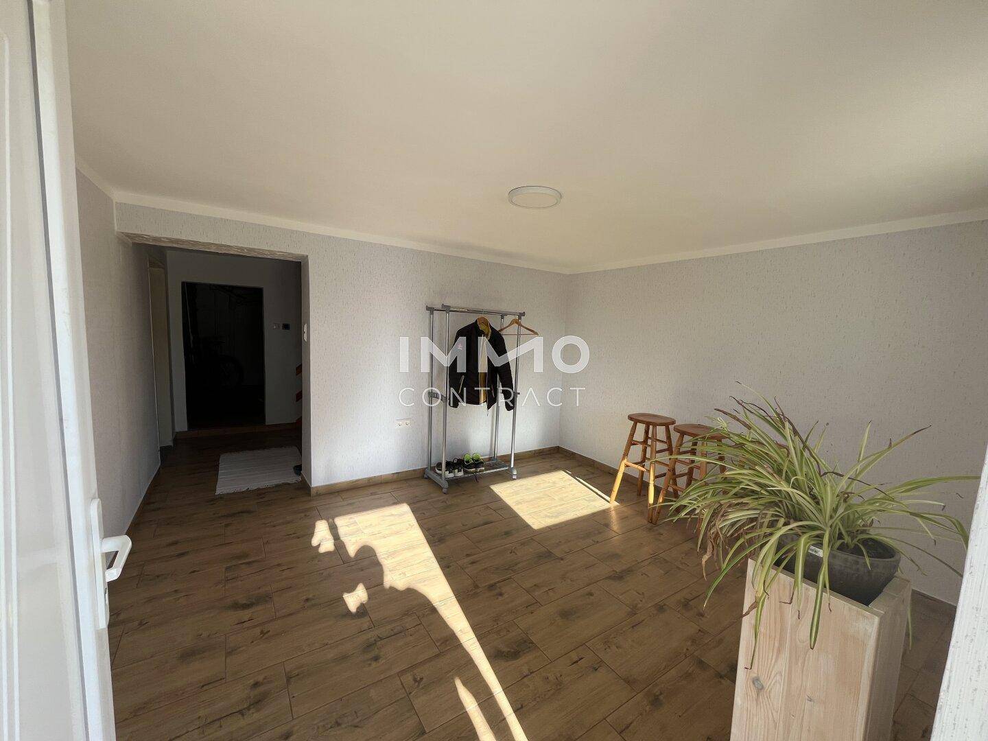 Heller Eingangsbereich mit Holzoptik-Fliesenboden und einfacher Garderobe.