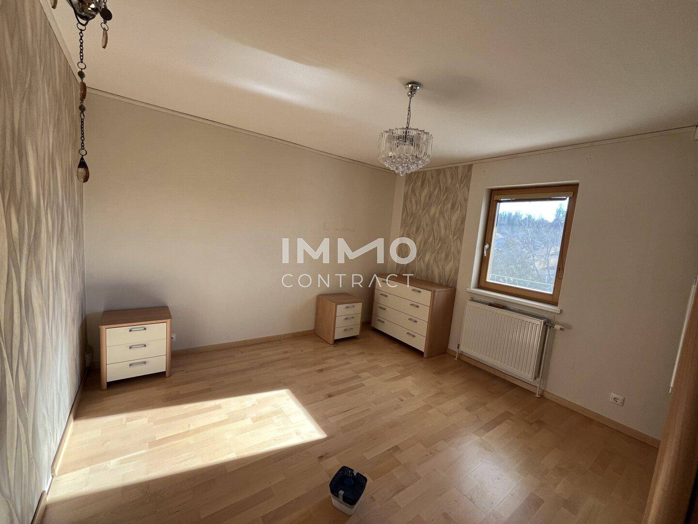 Geräumiges Schlafzimmer mit Parkettboden, Fenster und viel natürlichem Licht.