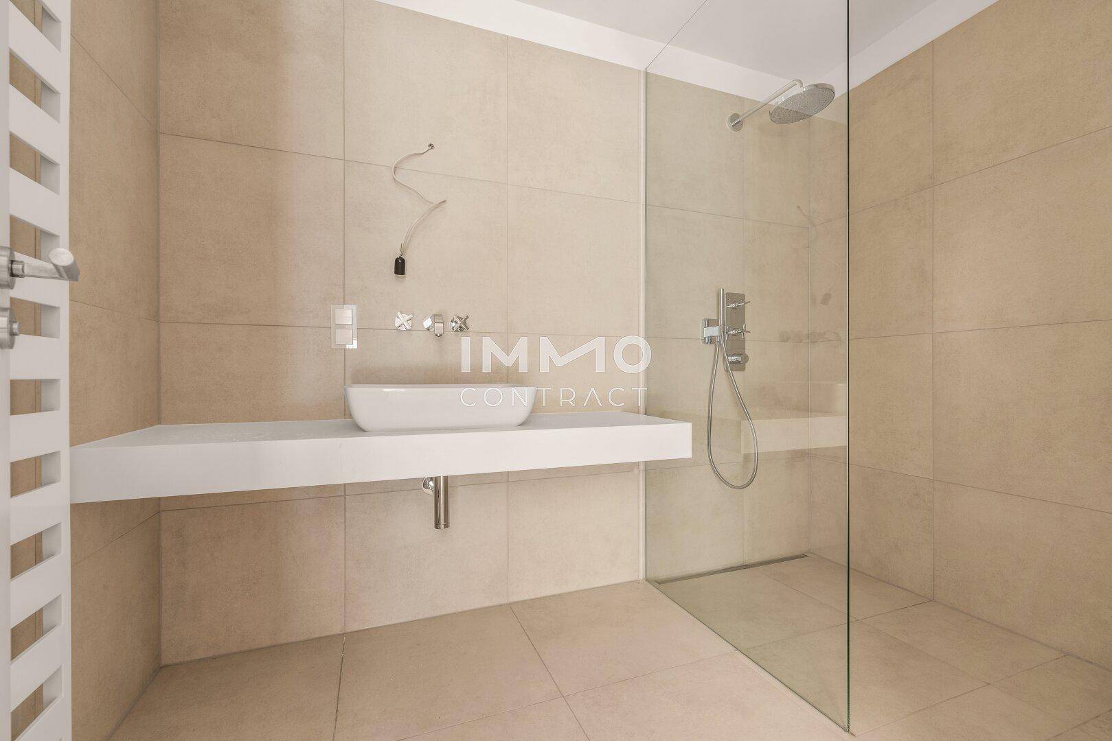 Detailansicht des modernen Badezimmers mit Doppelwaschbecken und großzügiger begehbarer Dusche.