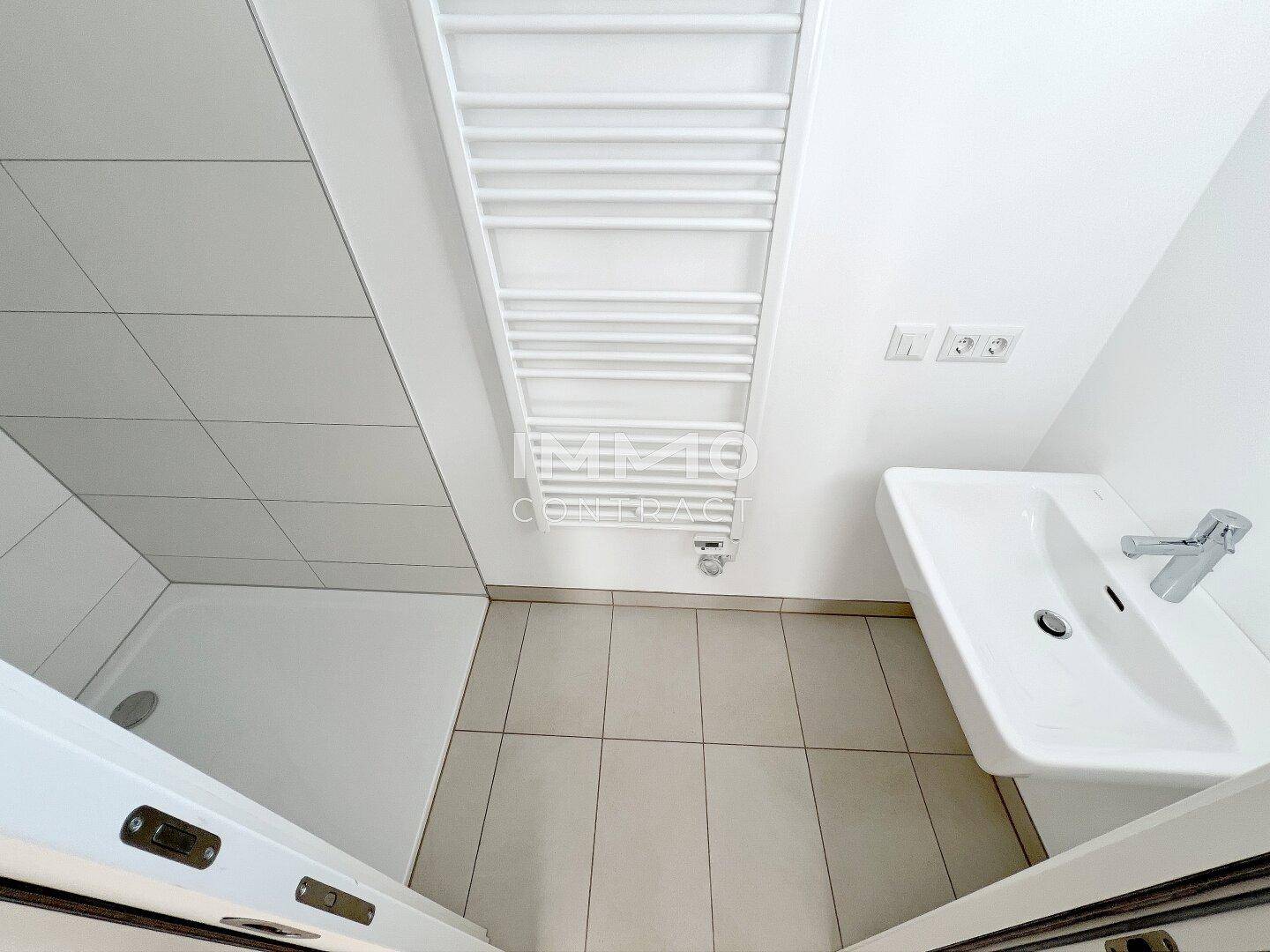 Modernes Badezimmer mit ebenerdiger Dusche, Einzelwaschbecken und beheiztem Handtuchhalter.