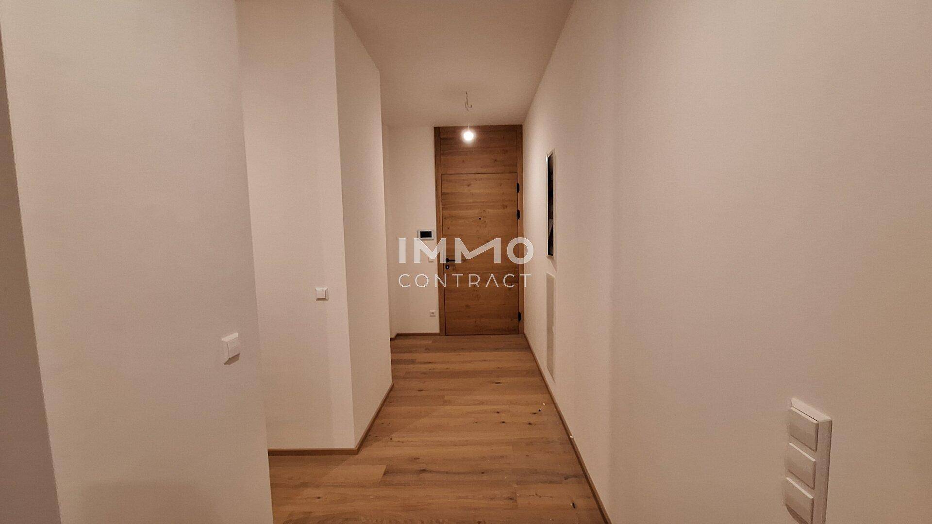Heller Flur mit Holzboden und moderner Holztür, der zu weiteren Räumen führt.