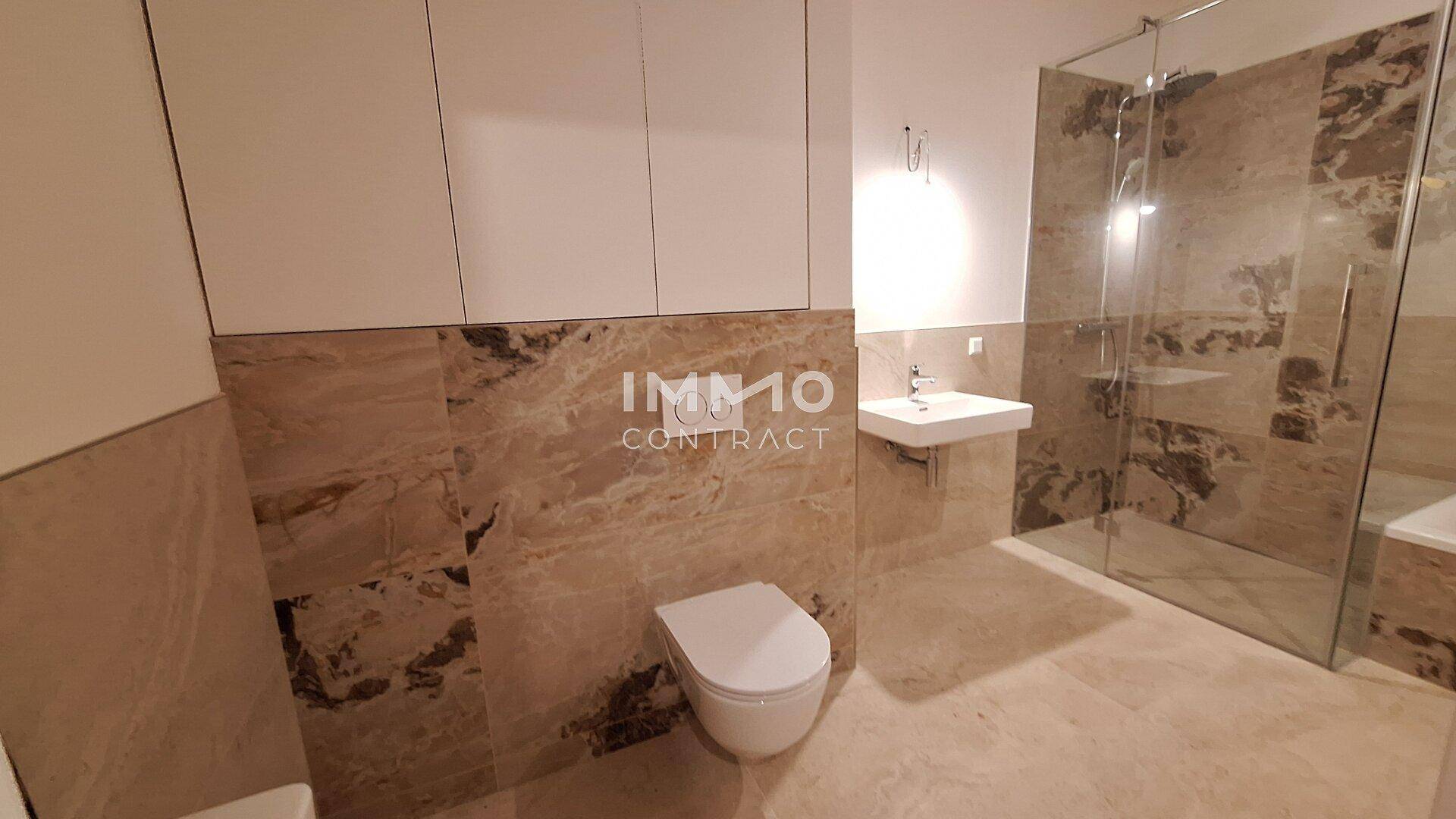 Modernes Badezimmer mit wandhängendem WC, Waschbecken und großer Duschkabine.