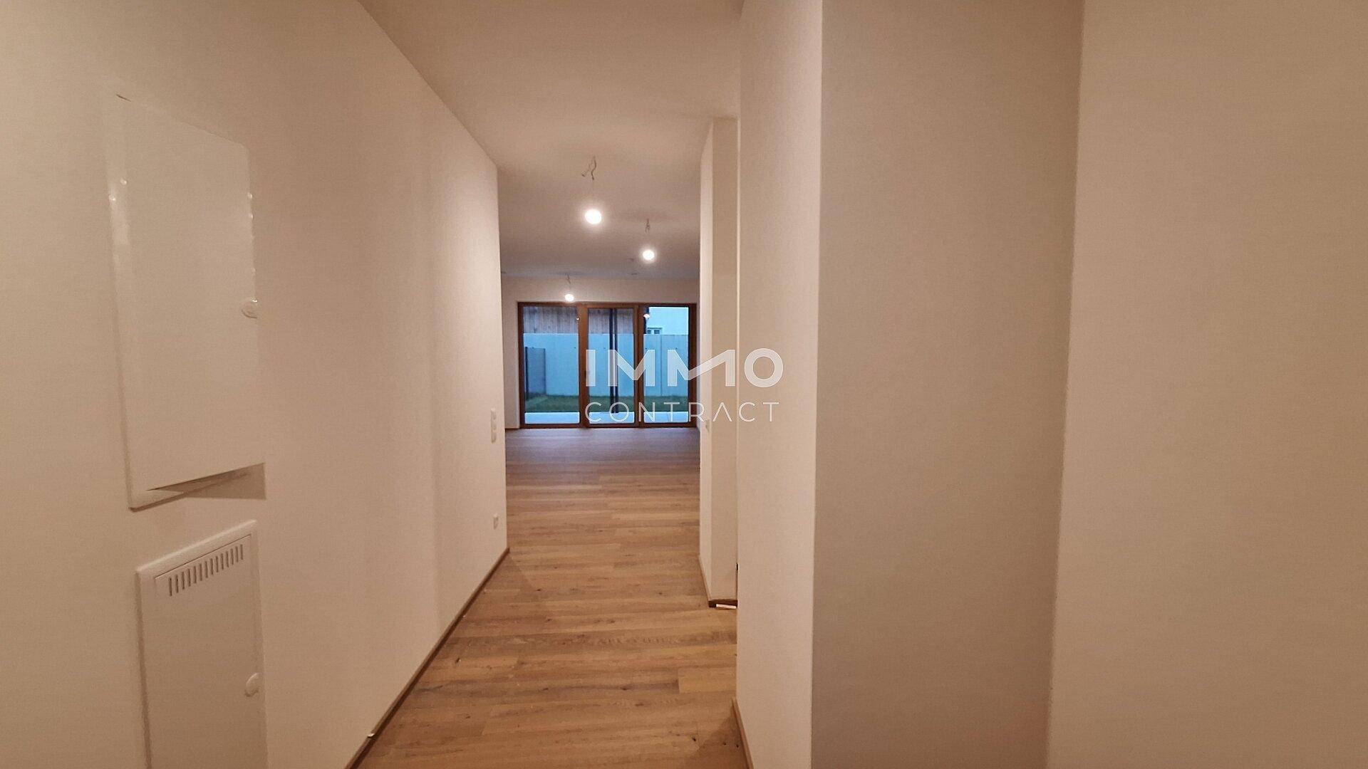 Langer, heller Flur mit Holzboden und Blick in den Wohnbereich mit Terrassenzugang.