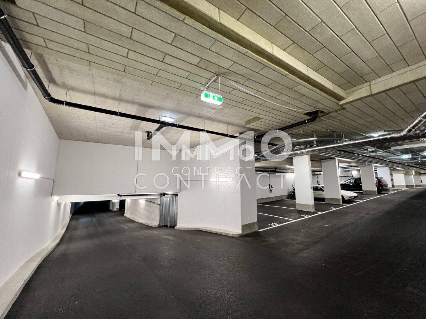 Tiefgarage mit zahlreichen Stellplätzen, Betonwänden und Decken sowie Beleuchtung.