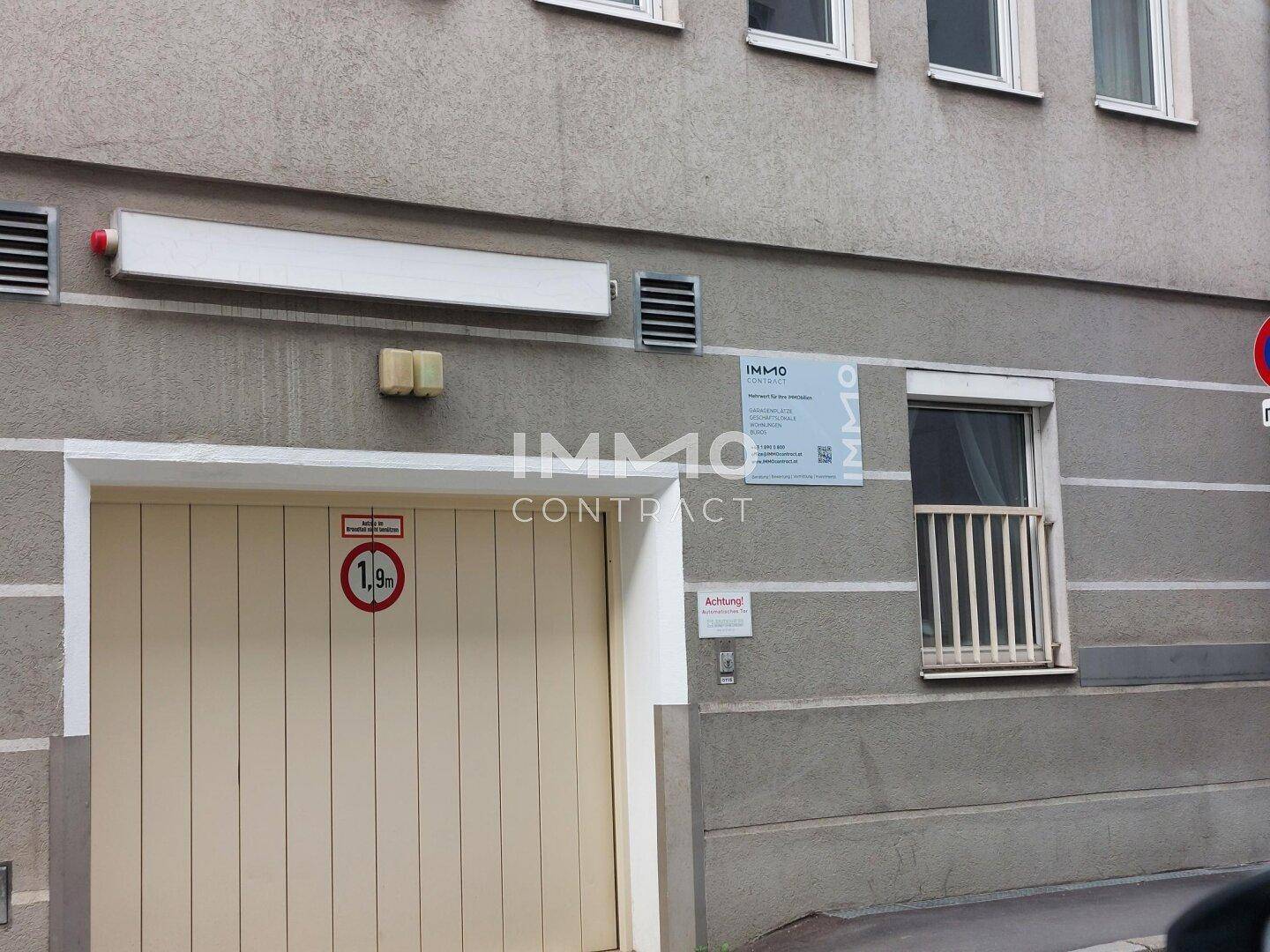 Eingang zur Tiefgarage an der Gebäudefassade mit Höhenbegrenzungsschild und Fenster.