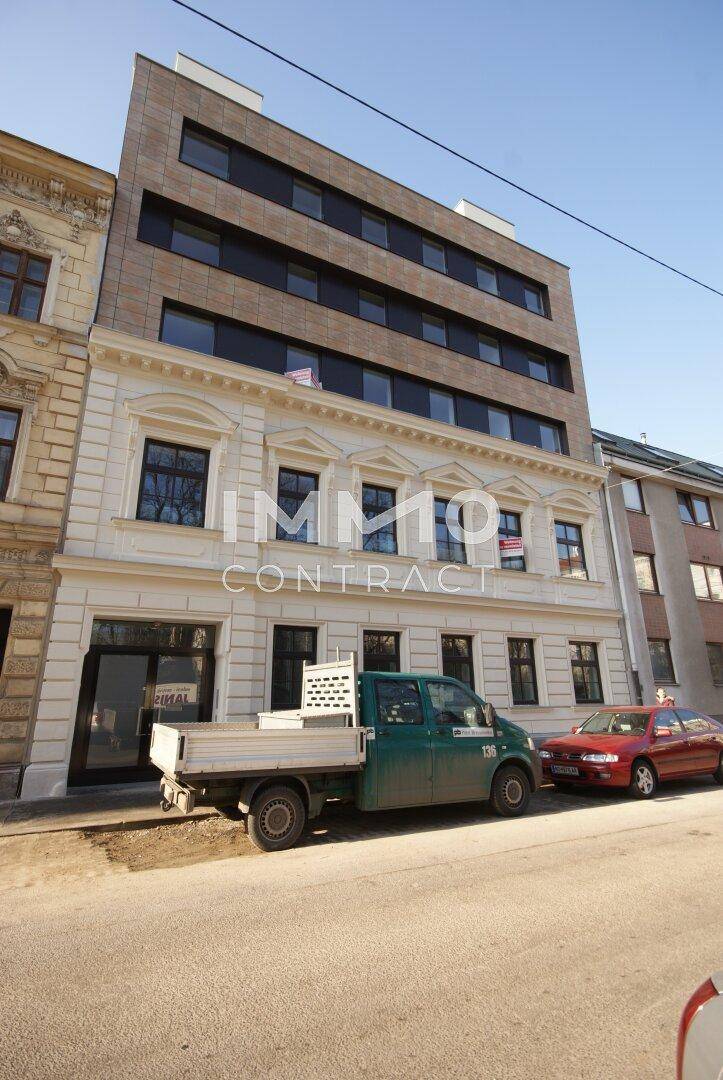 Die Gebäudefassade kombiniert historische und moderne Architekturelemente an einer städtischen Straße.