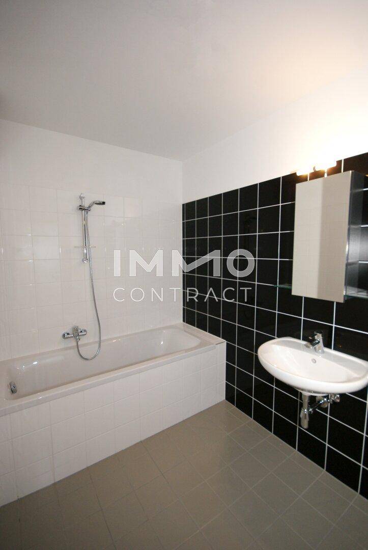 Modernes Badezimmer mit Badewanne, Waschbecken und schwarz-weißen Fliesen an den Wänden.