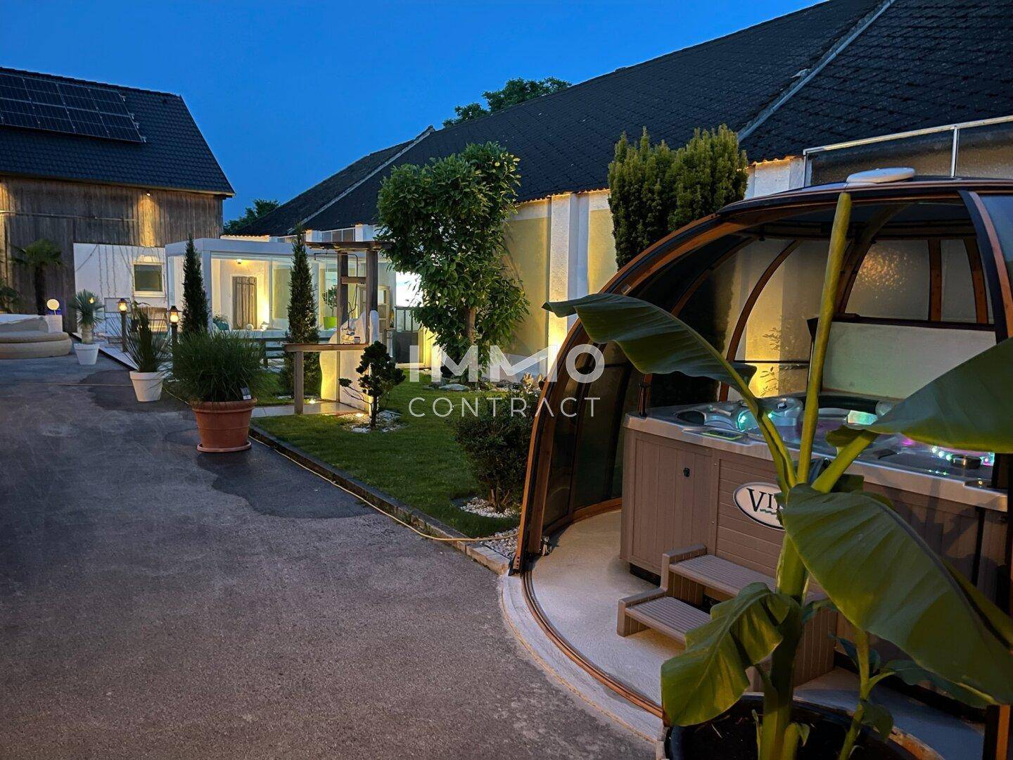 Weitläufiger Garten mit Whirlpool im Glaskuppel-Pavillon und weiteren Gebäuden im Hintergrund.