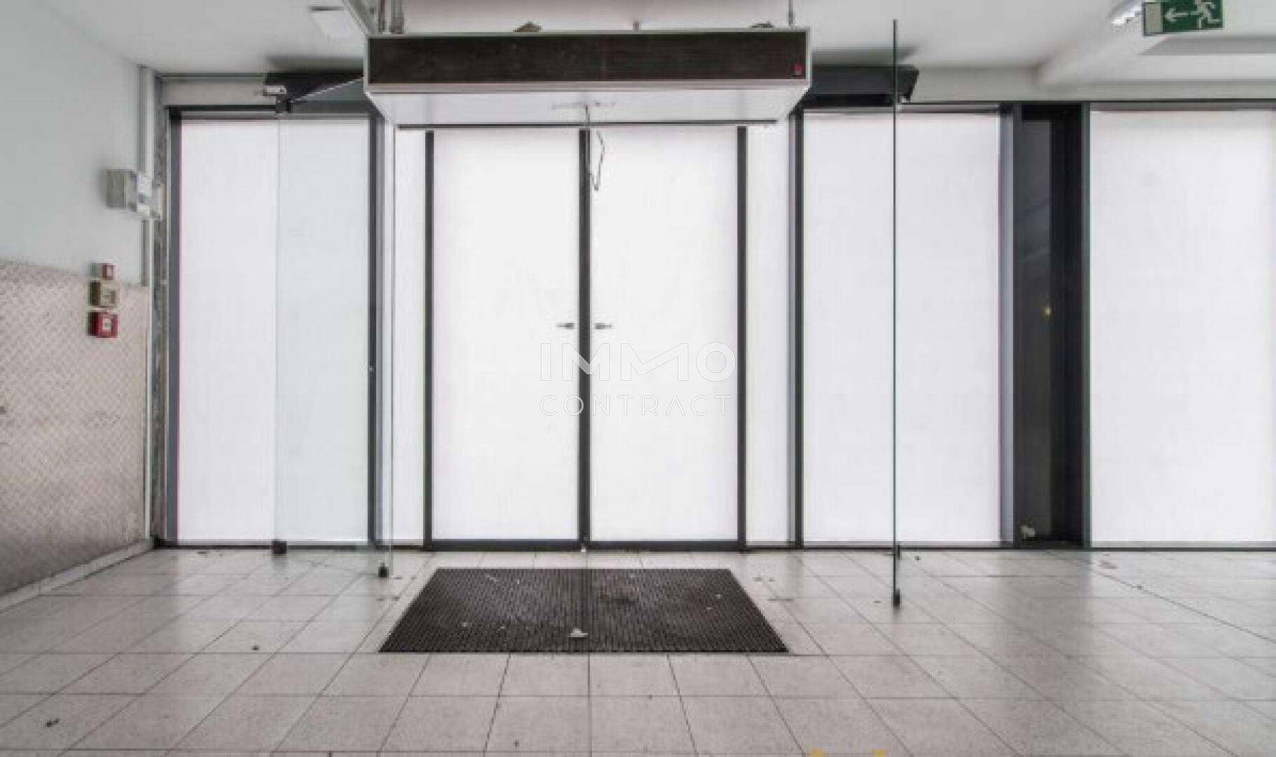 Eingangsbereich eines Gewerberaums mit großen Glastüren und Fliesenboden, bereit für Kunden und Besucher.