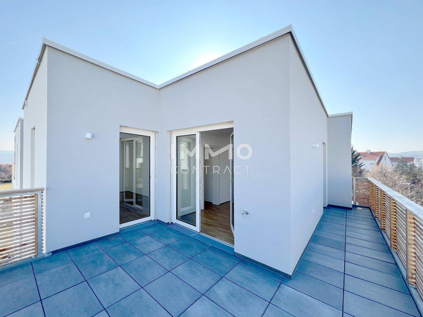 Große Terrasse mit Zugang zu den Innenräumen, modernen Fliesen und Holzgeländer.