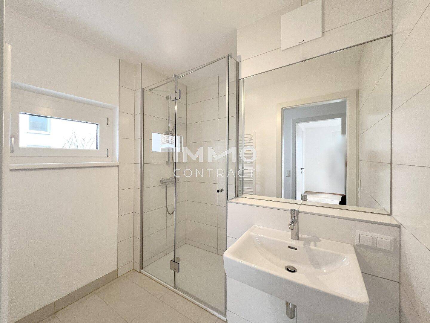 Modernes Badezimmer mit Dusche, Waschbecken und Fenster für Tageslicht.