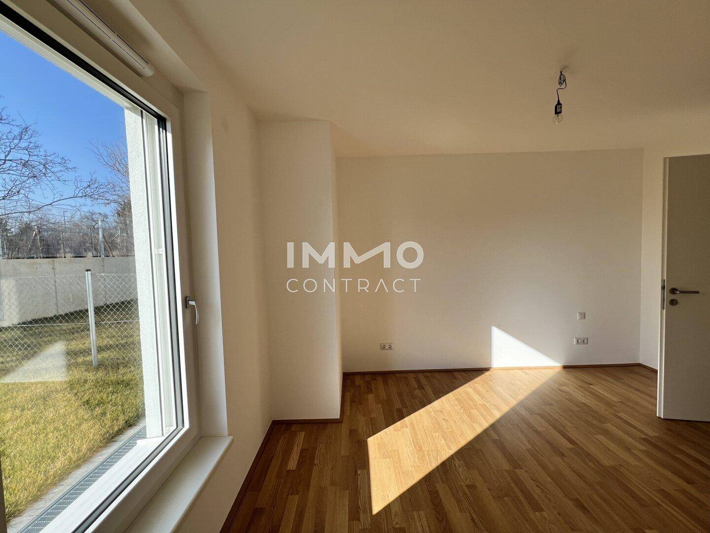 Sonniges Zimmer mit Parkettboden und großem Fenster, das viel Tageslicht hereinlässt.