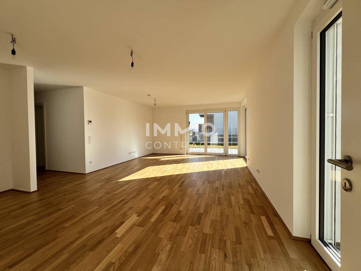 Lichtdurchfluteter Wohnbereich mit Eichenparkett und großen Fensterfronten zum Außenbereich.