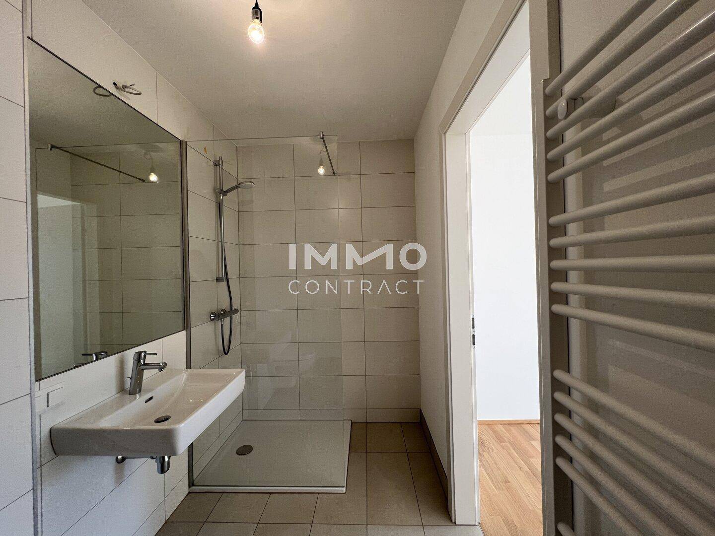 Modernes Badezimmer mit bodengleicher Dusche, großformatigen Fliesen und Handtuchheizkörper.