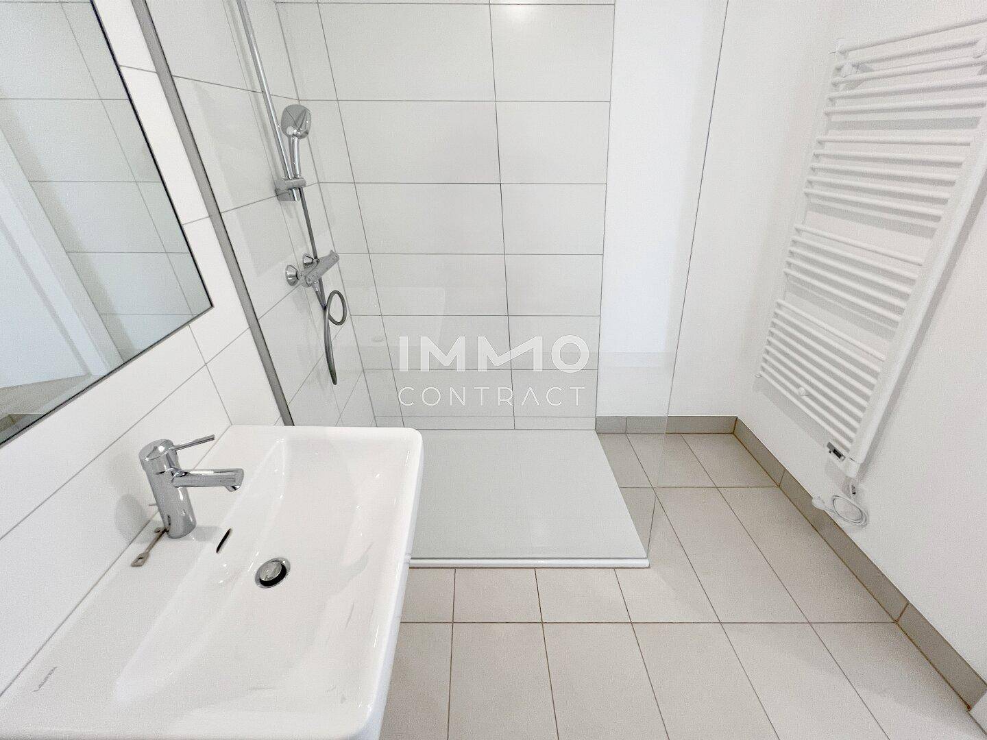 Detaillierte Ansicht des Badezimmers mit Duschbereich und modernem Waschbecken.