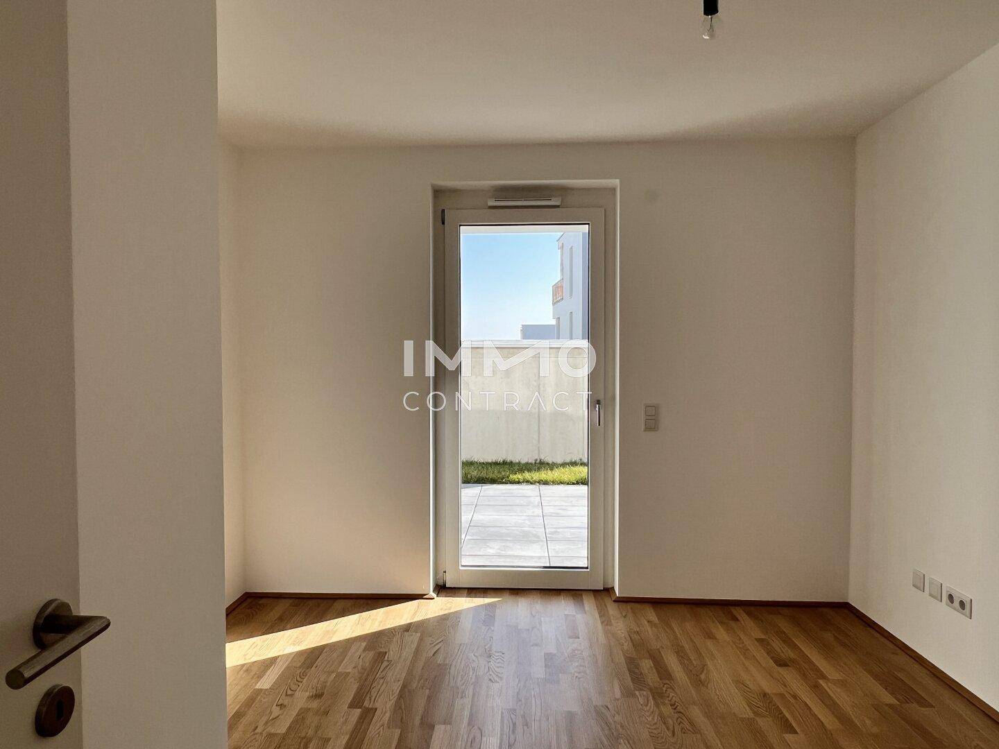 Helles Zimmer mit Parkettboden und direktem Zugang zu einem privaten Außenbereich.