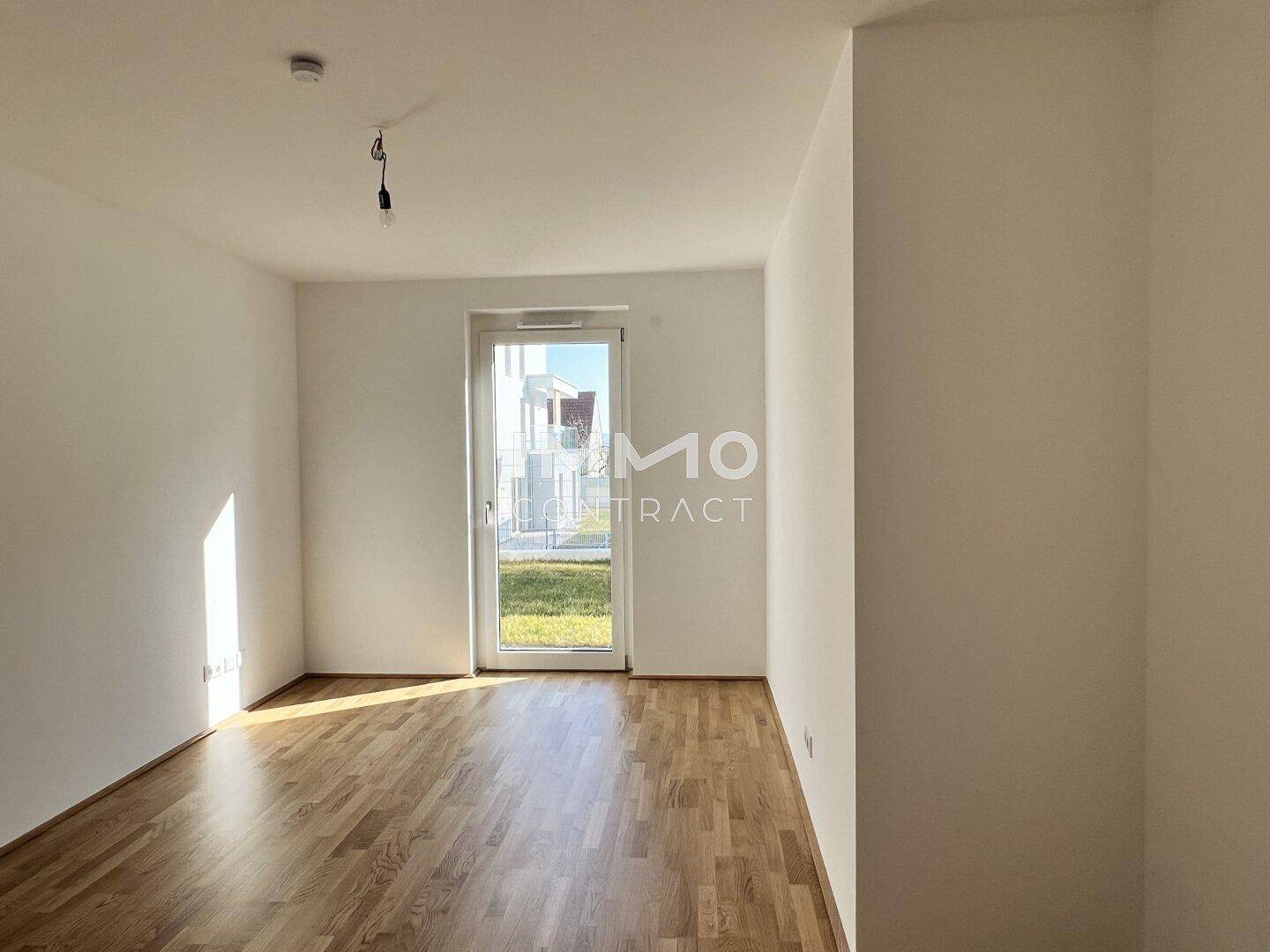 Geräumiges Zimmer mit Parkettboden und Tür zum Garten, ideal für direkten Zugang ins Freie.