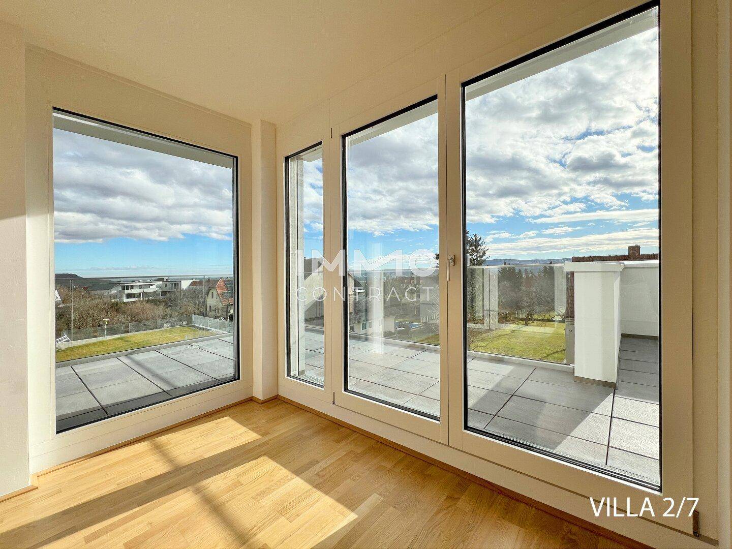 Helles Wohnzimmer mit großen, bodentiefen Fenstern und Zugang zur sonnigen Terrasse.