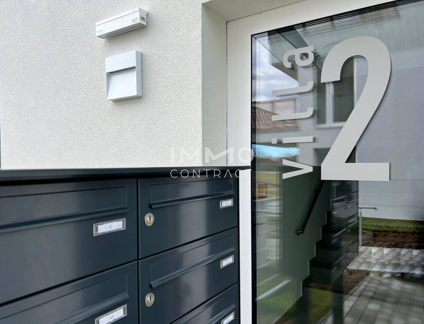 Moderner Eingangsbereich mit Briefkästen und der Nummerierung der Villa.