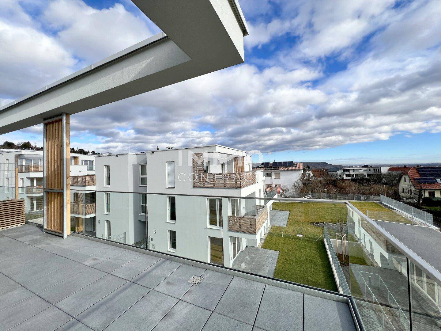 Moderne Wohnanlage mit mehreren Terrassen und begrünten Dachflächen unter blauem Himmel.