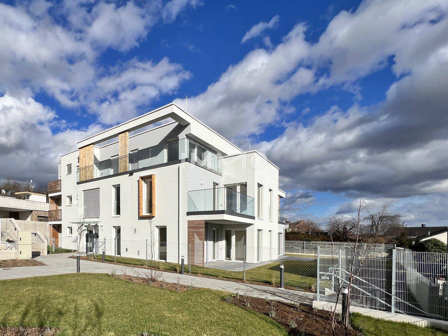 Neubau-Wohngebäude mit moderner Architektur, großen Fenstern und Balkonen in sonniger Umgebung.