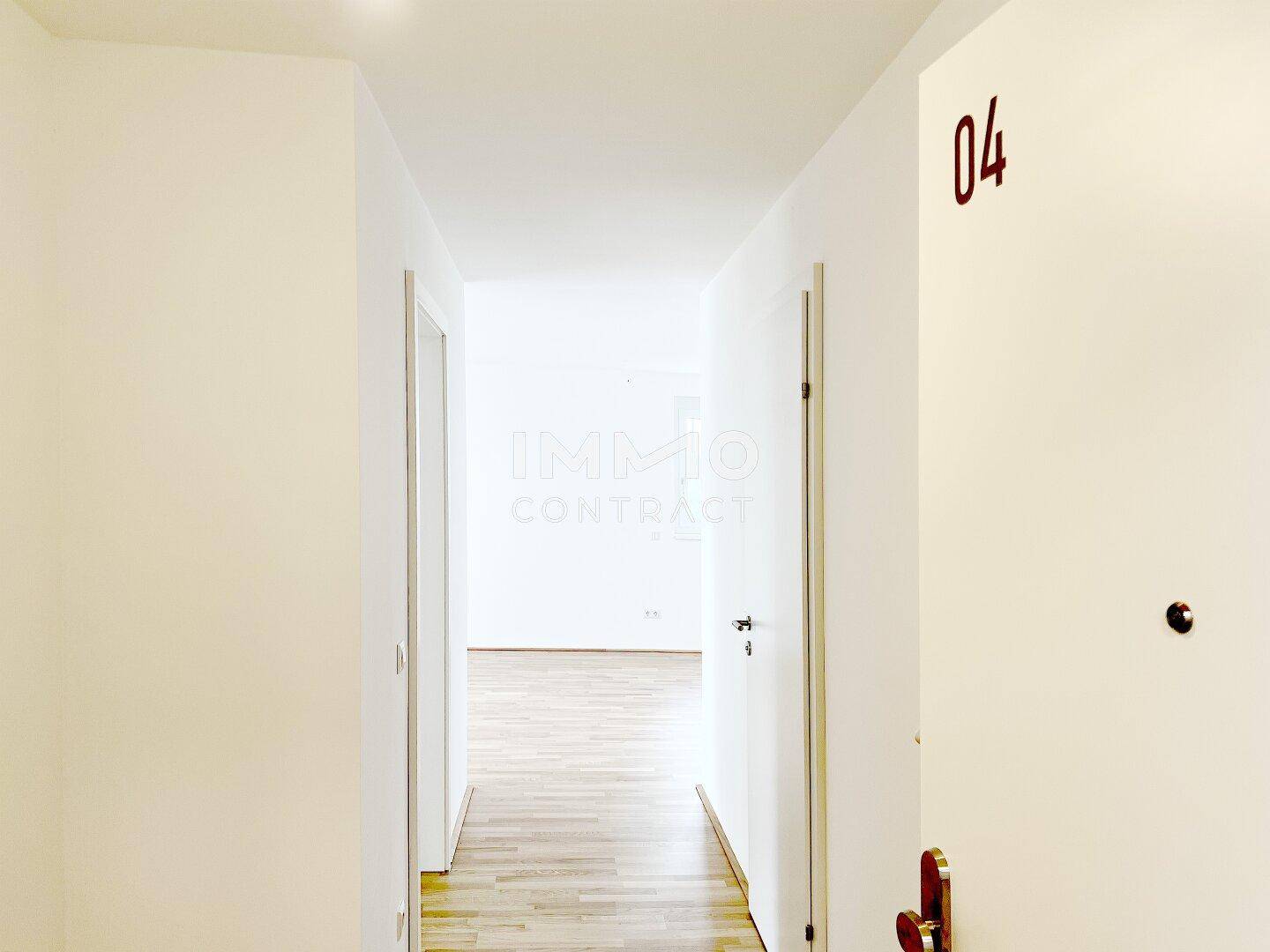 Heller Flur einer Neubauwohnung mit Parkettboden und Zugang zu weiteren Räumen.